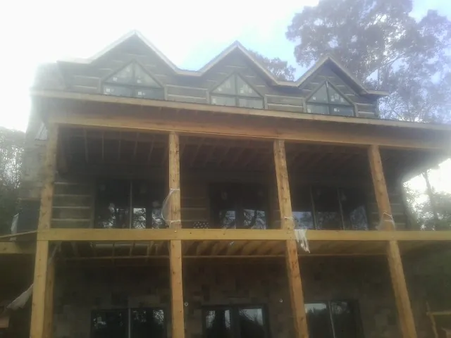 Dormers and porch framing on a large log home under construction — Roof Coating work by our crew in Denhoff