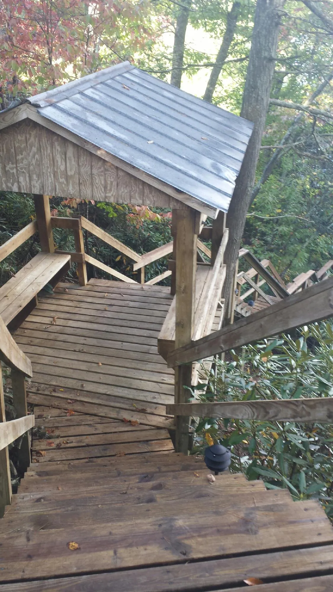 Metal roofed shelter over wooden steps on a wooded walkway — Skylight Repair & Installation work by our crew in Denhoff