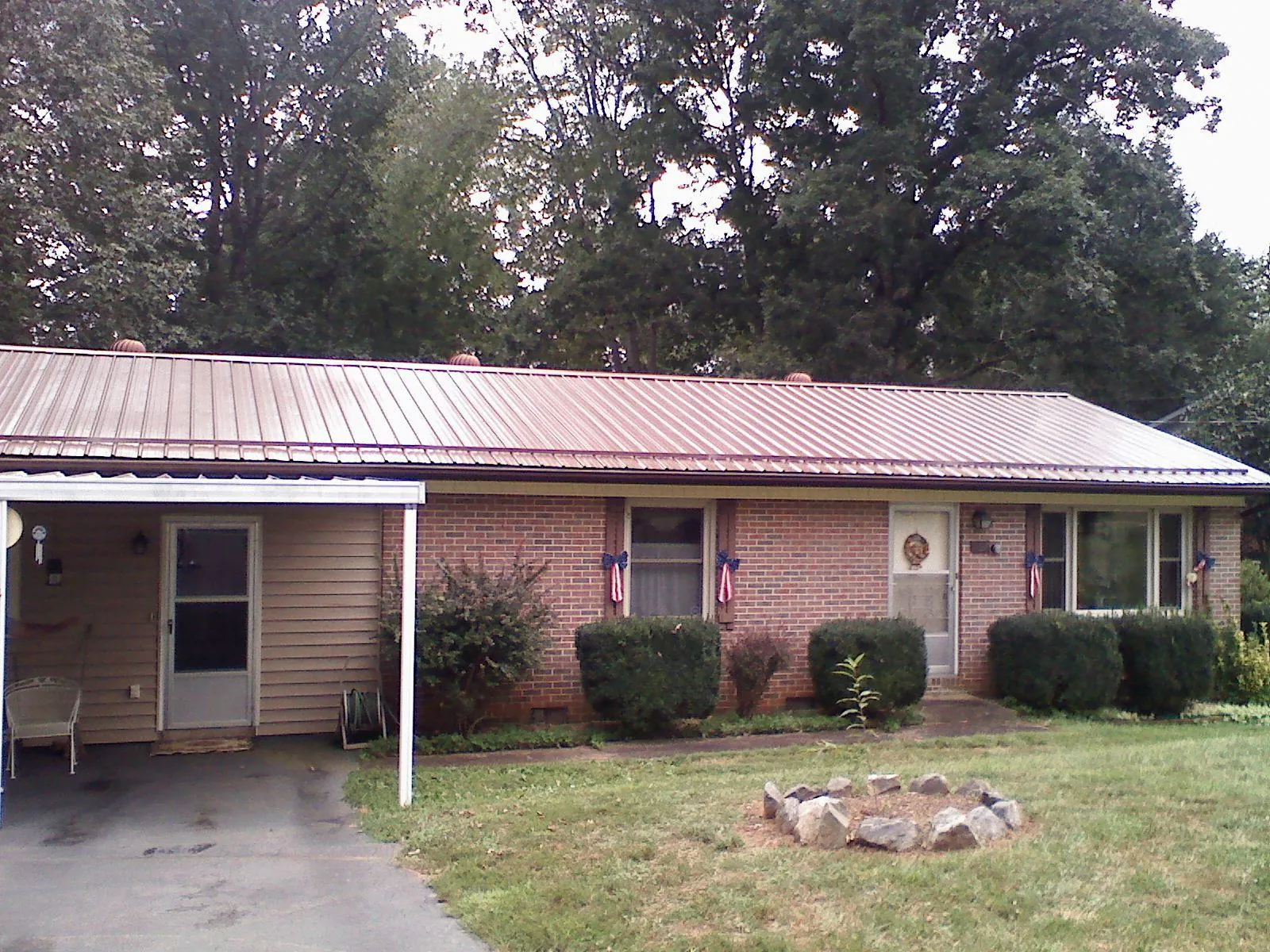 Bronze metal roof and carport on a brick ranch home — Roof Repair work by our crew in Denhoff